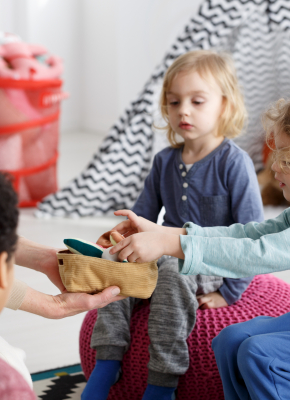 Little kids and their teacher cleaning toys after play